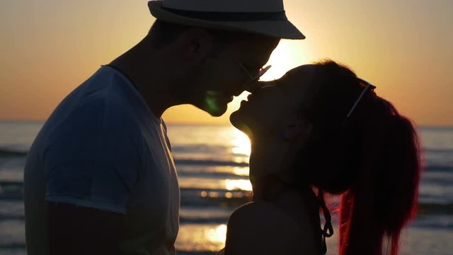 Beautiful young couple teasing one another and kissing at sunset