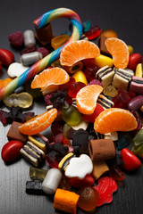 Candy cane with gummy marmelade candies and tangerine slices on