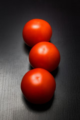 Fresh whole tomatoes on black background