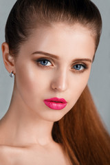 Beautiful Brunette Woman portrait. Beauty Luxury Makeup and sexy Pink Lips. Fashion Model on a gray background. Blue eyes