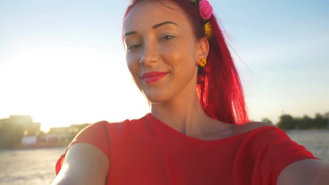 Young beautiful redhead posing on a beach and taking a selfie