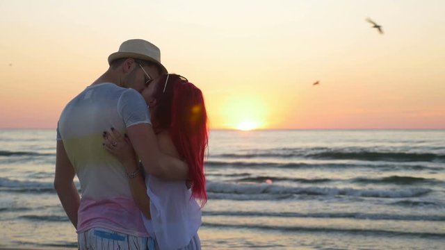 Young beautiful couple kissing at twilight on the beach