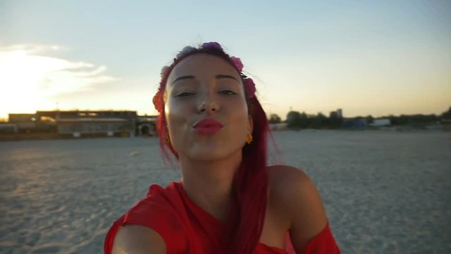 Beautiful young woman taking a selfie on beach at sunset