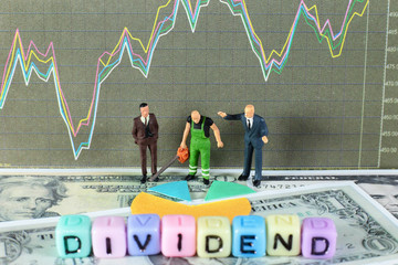 A sawyer is cutting the dividends for two business men. Conceptual image of the word "dividend" with stock chart and dollar background.
