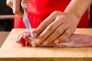 Chef cutting raw pork on wooden board prepared for cooking