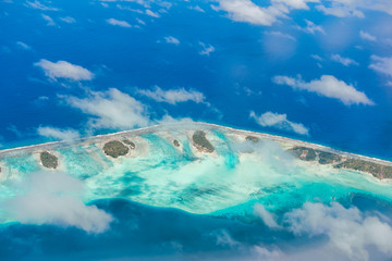 Aerial view of the island with clouds, reef and lagoon. Island n