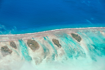 Aerial view of the island with clouds, reef and lagoon. Island n
