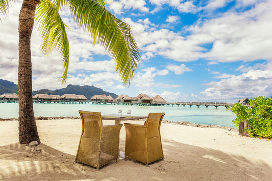 Two chairs and table on a sand beach with a view on the lagoon a