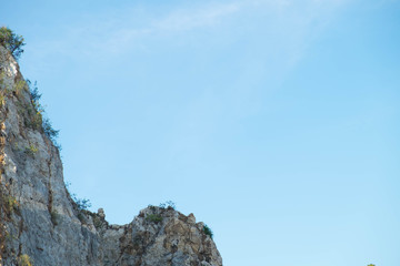 Mountain peaks covered and cliff with forest and bright sky with a white cloudy.