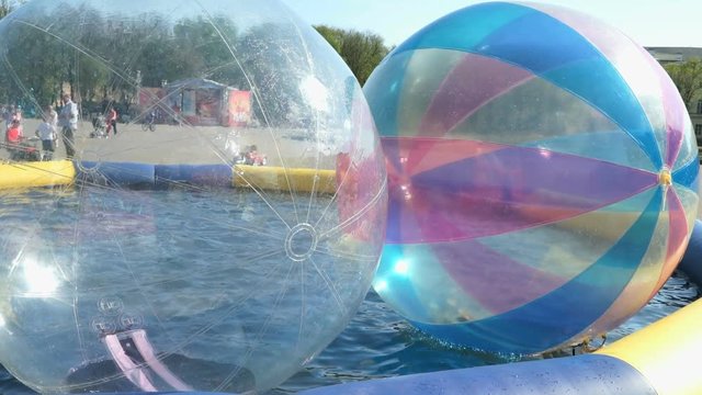 Little girl inside the big inflatable ball floating on water surface outdoors
