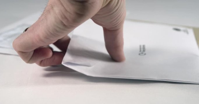 Adult male picks up a household bill. Filmed on white