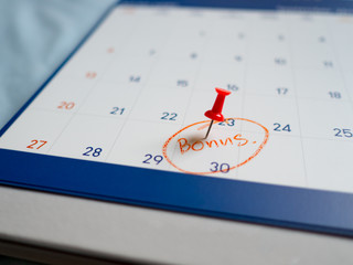 Red pin push on day 30 of end month on white calendar. Mark this day as bonus date.