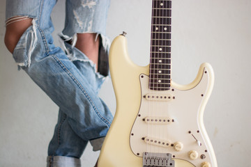 .A young man with an electric guitar Leaning against a cement wa