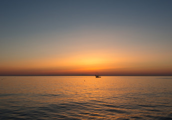 Fishing boats pull their nets at the sunrise. Adriatic cost. Emilia Romagna. Italy.