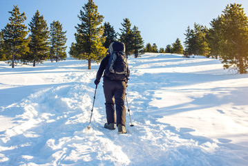 man hiker going in the mountains through the snow