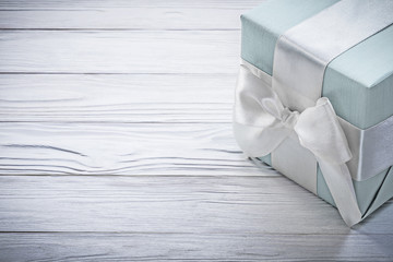 Blue gift box with white knot on wooden board celebrations conce