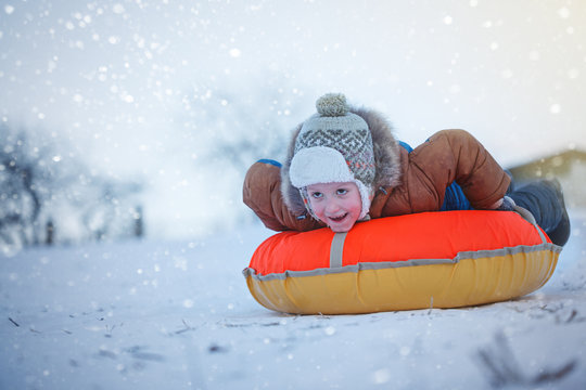 Cute boy sliding with tubing in the snow, wintertime, happiness concept.