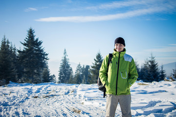 Fototapeta na wymiar Man backpacker walking in winter mountain forest
