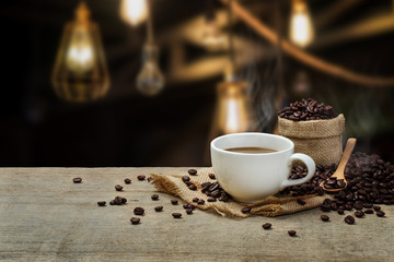 Hot Coffee cup with Coffee beans on the wooden table and the cof