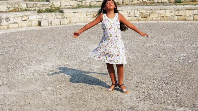 Little lively girl dances in the park - satisfied - joy. Slow motion