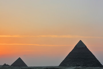 Fototapeta na wymiar Dramatic sunset behind distant Egyptian pyramids in Giza, Cairo, Egypt