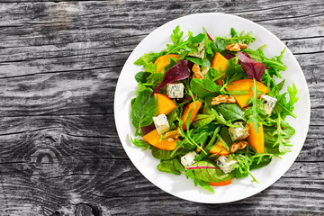 persimmon salad with lettuce leaves, blue cheese and walnuts