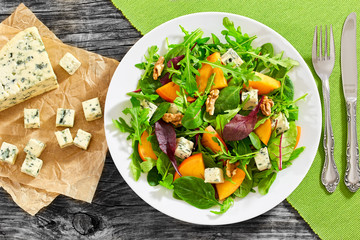 salad with persimmon slices, mix of lettuce leaves, blue cheese