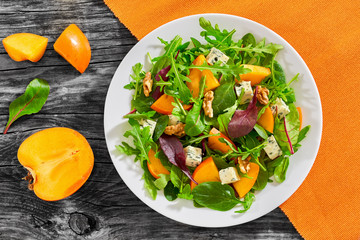salad with persimmon slices, mix of lettuce leaves, blue cheese
