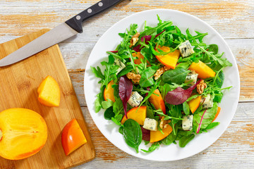 salad with persimmon slices, mix of lettuce leaves, blue cheese