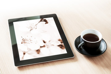 Tablet pc mock up with screen floral wallpaper, at the desk with a cup of coffee