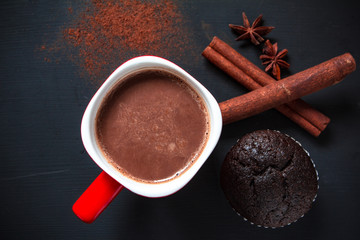 Hot chocolate in red cup with chocolate cup cake on black backgr