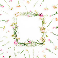 Wreath frame made of pink and beige wildflowers, green leaves, branches on white background. Flat lay, top view. Valentine's background