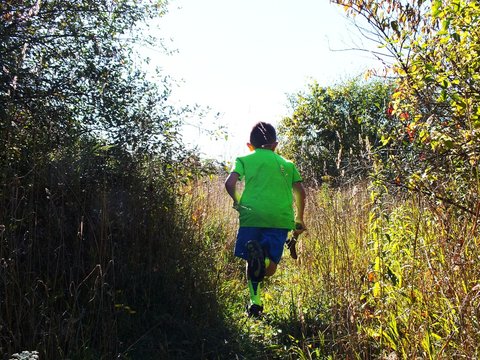 Boy running away through field