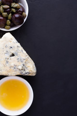 cheese, honey and olives on a black background