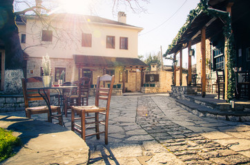 Fototapeta na wymiar Small traditional paved square with cafe and authentic narrow streets in Nissaki, Ioannina, Greece