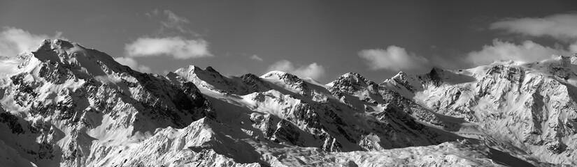 Black and white panoramic view on snowy mountains in sunny day
