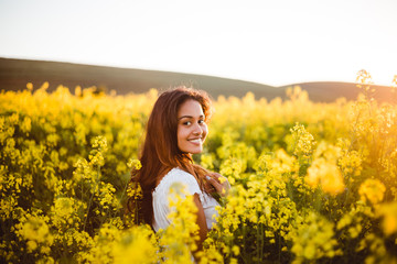 Naklejka na ściany i meble Young girl in yellow flower field