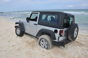 Fototapeta na wymiar A silver off road vehicle stuck in the sand in Cancun, Mexico.