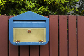 Blue mailbox with on brown wooden fence