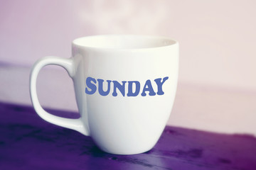 white cup with the word Sunday on it