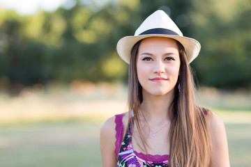 Beauty Romantic Girl Outdoors. Beautiful young brown hair model dressing a white panama hat at park in Sun Light. Summer portrait. Glow Sun, Sunshine.