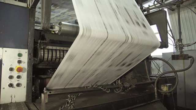 Long uncut paper on rolling machine in printing house.