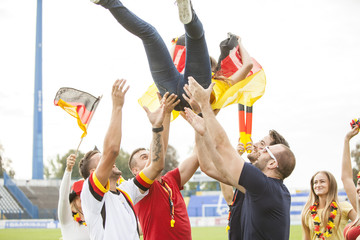 Enthusiastic fan crowd surfing on soccer field