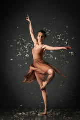 Fototapeta na wymiar girl dancing barefoot with feathers. ballet. grey background