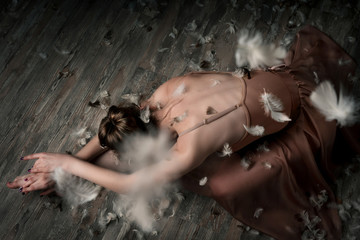 girl dancing barefoot with feathers. ballet. grey background

