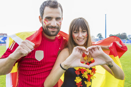Young couple with face paint waving Spanish flag