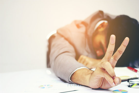 Businessman sleeping at his desk working over a laptop after he work all day all night, Tried overworked, Keep fighting in business concept.