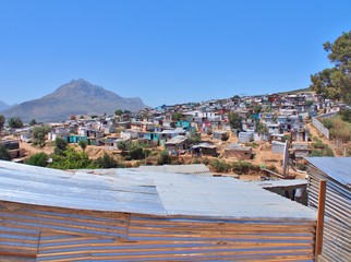 Informal settlement - Enkanini with mountain and blue sky on the outskirts of Stellenbosch, Western Cape province, South Africa. Many shacks in Enkanini have solar panels for access to electricity.