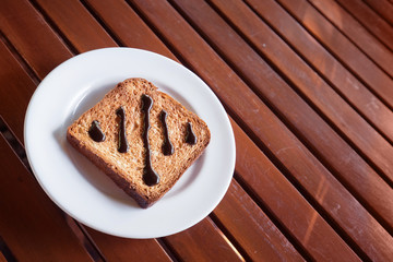 Chocolate Spread on Toast in white disk on wood table