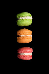 Multicolored macaroons falling or flying isolated on black background. Free space for text